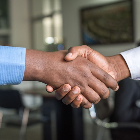 Close-up of two hands shaking in a professional handshake, symbolizing a business partnership and collaboration in a corporate environment.