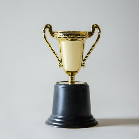 A shiny gold trophy with handles on a black base, symbolizing achievement and success.